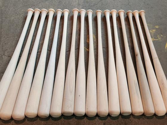 Kunstwerk von D'Ette Nogle: mehrere nebeneinander auf dem Boden liegende Baseballschläger, künstlerisch arrangiert, Betonboden im Hintergrund.