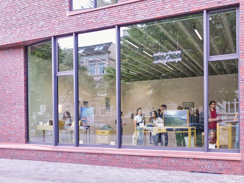 Blick durch das Schaufenster des Ausstellungsraumes mit Eröffnungsgästen