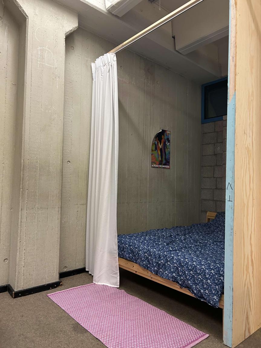 Die Schlafecke ist durch einen Vorhang vom Rest der Wohnung abgetrennt