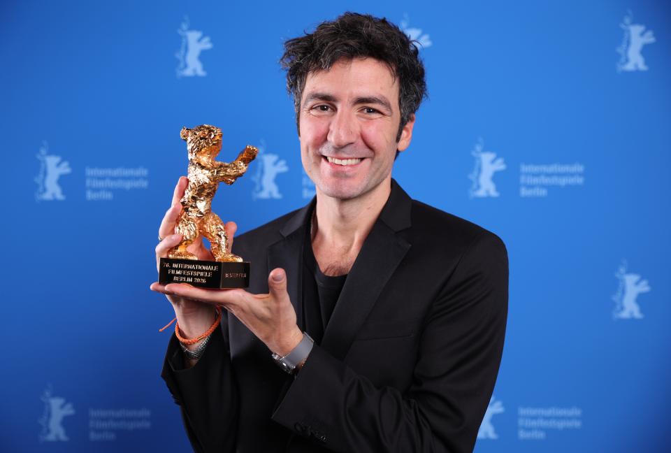 Porträtfoto einer Person mit Goldener-Bär-Trophäe vor Berlinale-Fotowand.