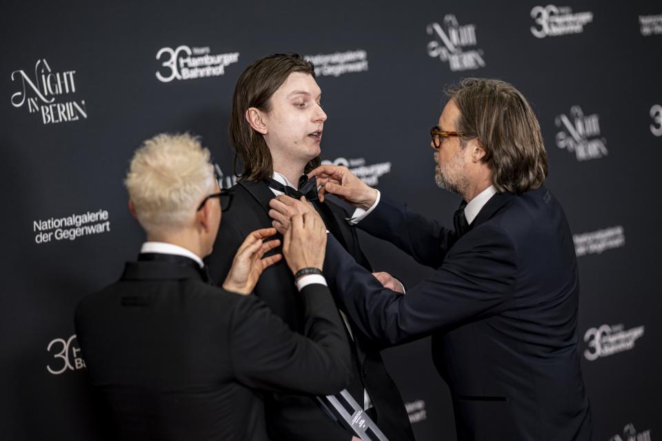 Jonas Roßmeißl, Preisträger des Hamburger Bahnhof Studio Award, wird von dem Hamburger-Bahnhof-Direktoren Till Fellrath (r) und Sam Bardaouil auf dem Roten Teppich der Gala "A Night in Berlin" die Fliege gerichte