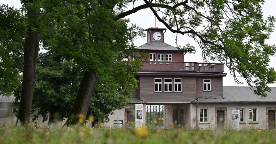 Gedenkstätte Buchenwald: Torhaus mit Uhrturm, Bäume und Wiese im Vordergrund.