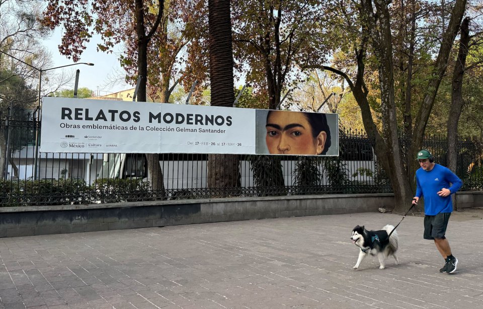 Ausstellungsbanner 'Relatos Modernos' mit Porträt; Läufer mit Hund auf dem Gehweg davor.