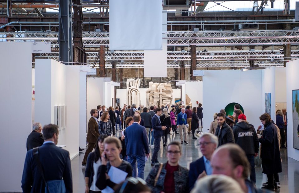 Kunstmesse in Industriehalle: Besucherströme im Mittelgang, weiße Galeriestände beidseits
