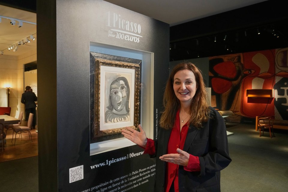 Frau zeigt auf gerahmtes Picasso‑Werk an Infowand