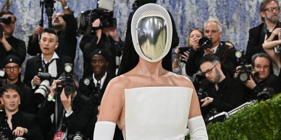 Foto einer Person mit verspiegelter Helmmaske in weißer Robe auf rotem Teppich; Fotografen dahinter.