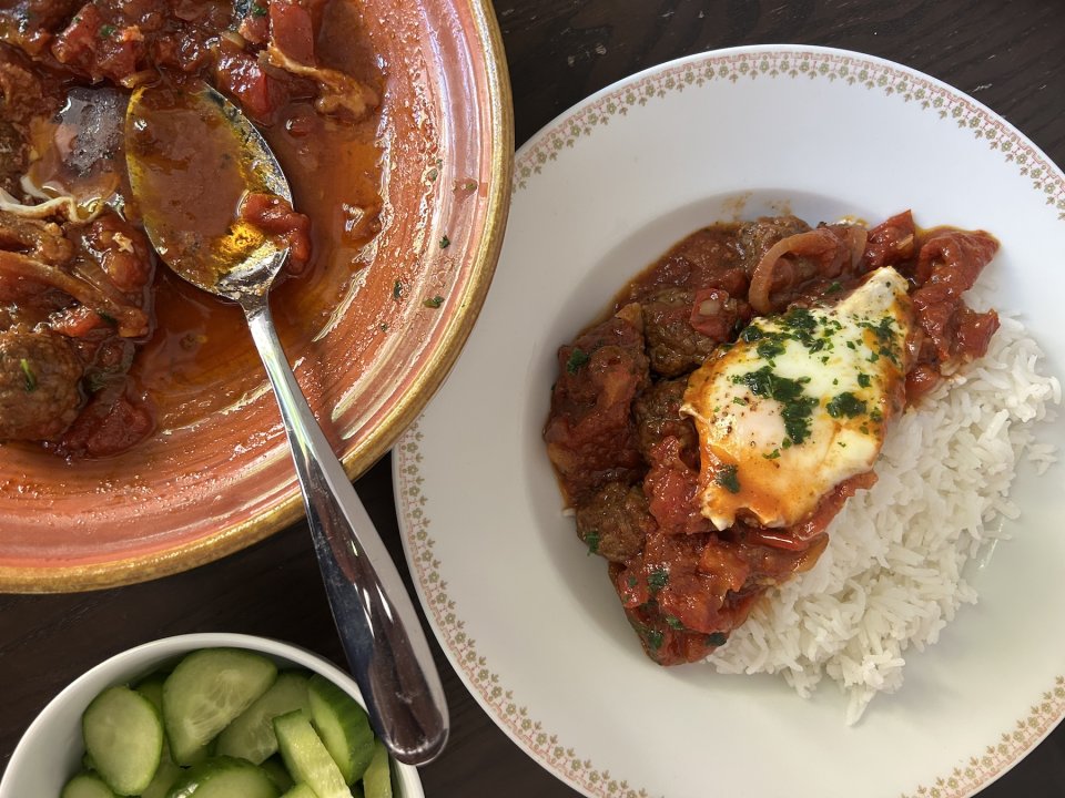 Foto: Fleischbällchen in Tomatensauce und Ei auf Reis; Schüssel mit Löffel, Gurkensalat.