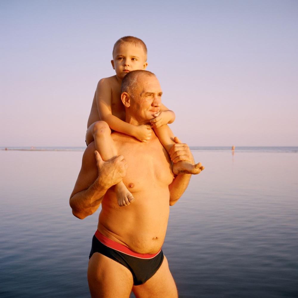 Sommer 2021. Mariupol, Ukraine. Artem und sein Sohn Matvey betrachten das Asow-Stahlwerk in Mariupol, wo Artem lange Zeit gearbeitet hat. Dieses riesige Kombinat aus der Sowjetzeit wurde später zum Zufluchtsort der letzten Soldaten, bevor die Stadt im Mai 2022 an die russischen Streitkräfte fiel