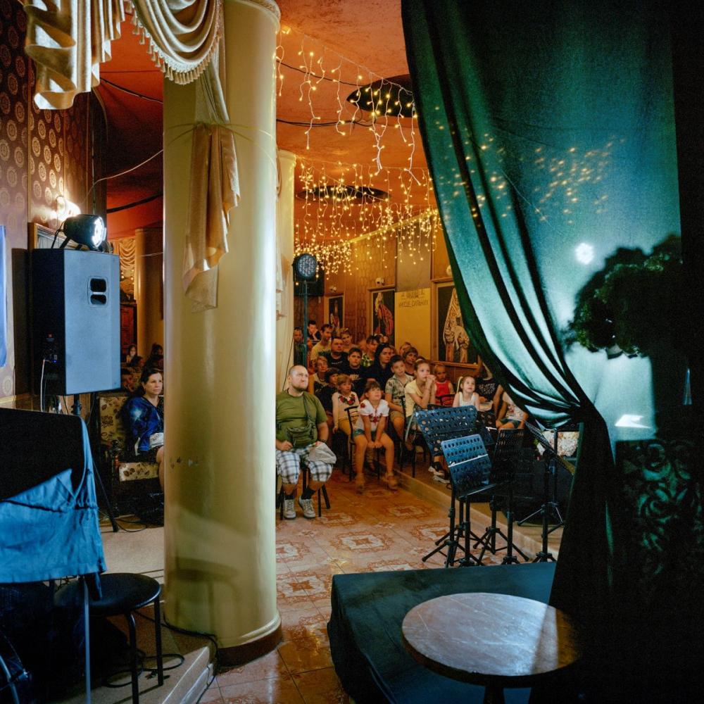 Sommer 2024. Ukraine. Am ukrainischen Nationalfeiertag schauen sich Familien im Keller des Chersoner Theaters Zeichentrickfilme an. Bei jedem Fliegeralarm müssen sie dorthin