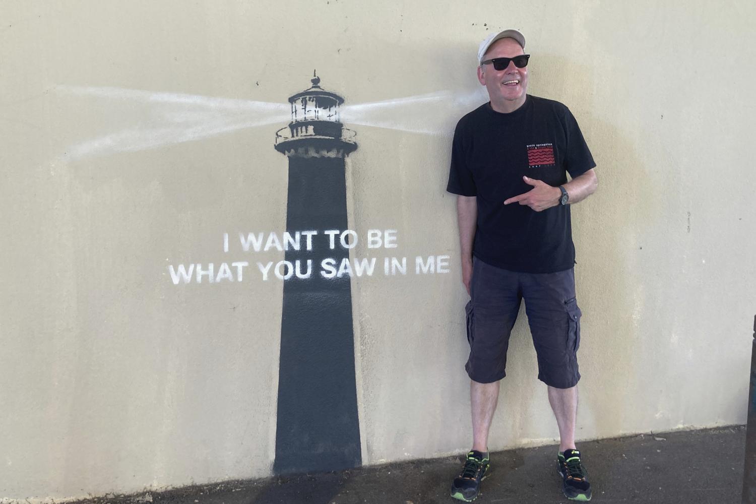 Ein Mann posiert vor einem Kunstwerk von Banksy in Marseille