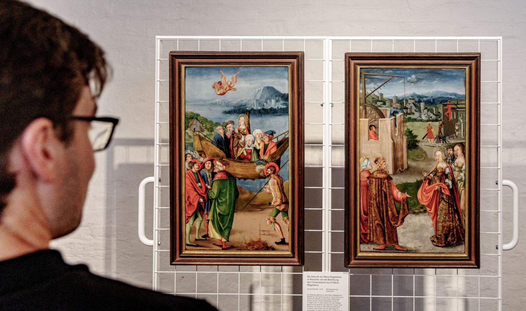 Besucher betrachten die zwei verschollen geglaubten Tafeln des Maria-Magdalenen-Rentabels