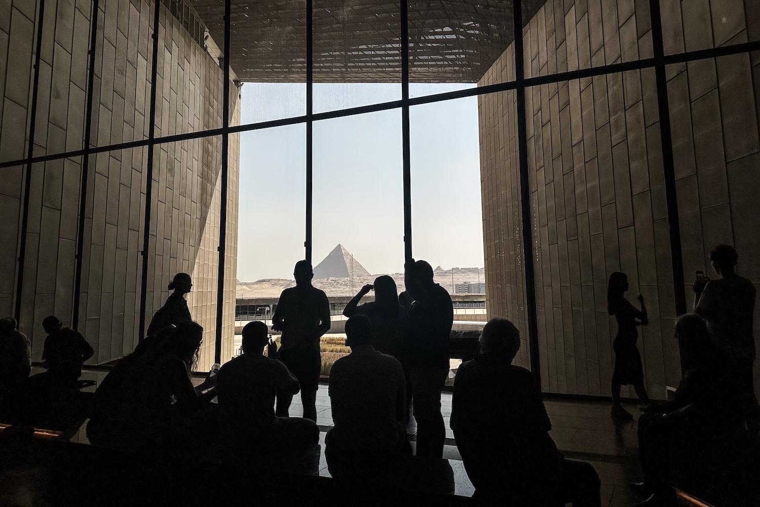 Besucher blicken aus dem Großen Ägyptischen Museum auf die Pyramiden von Gizeh