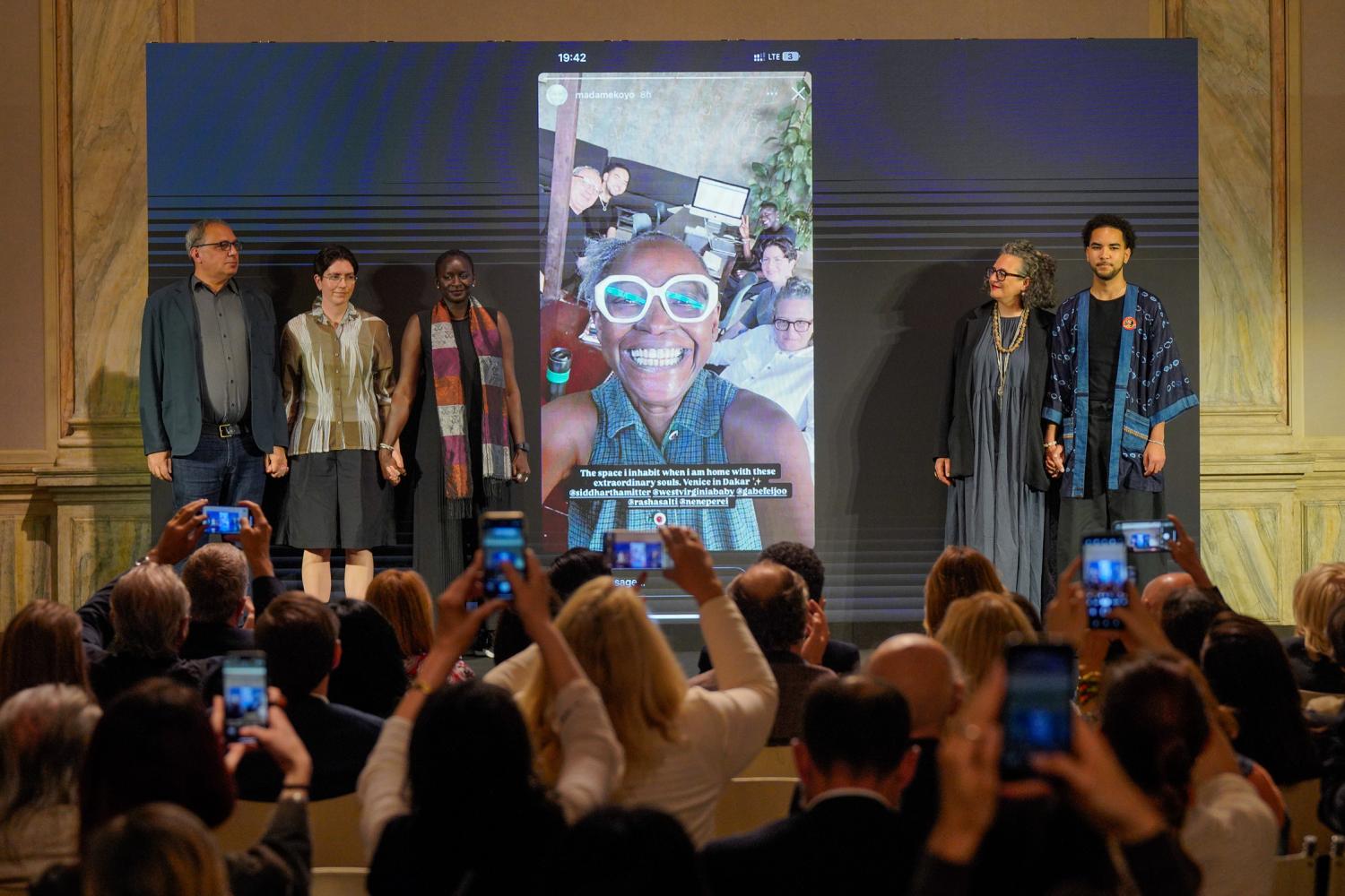 Das kuratorische Team der Venedig-Biennale 2026 vor einem Video der verstorbenen Kuratorin Koyo Kouoh im Mai 2026