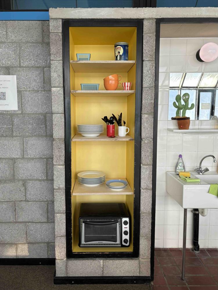 Ein in die Wand eingelassenes Regal mit Küchenutensilien und Mikrowelle