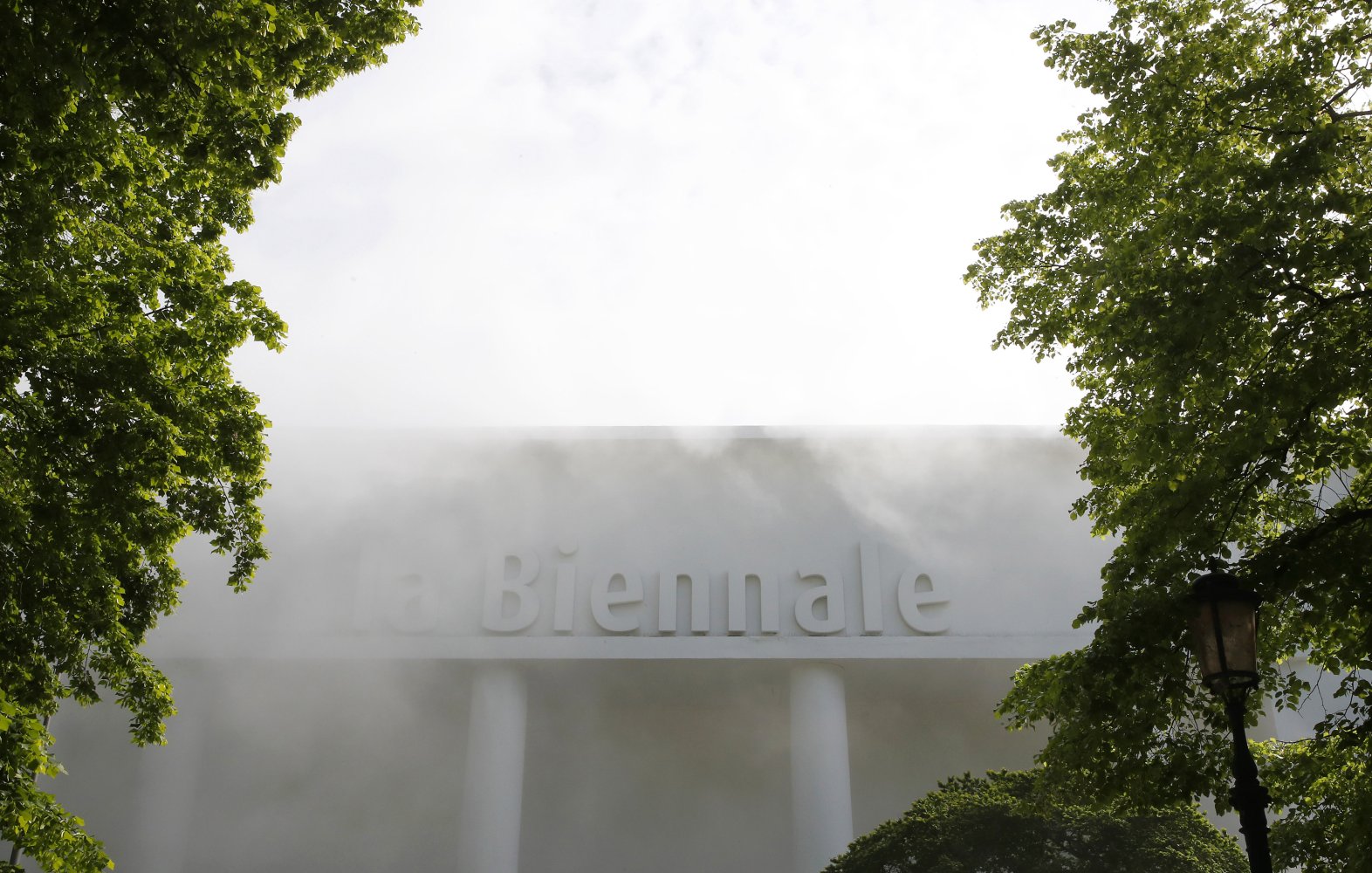 La Biennale di Venezia: Pavillonfassade mit Reliefschrift, im Nebel, zwischen Bäumen.