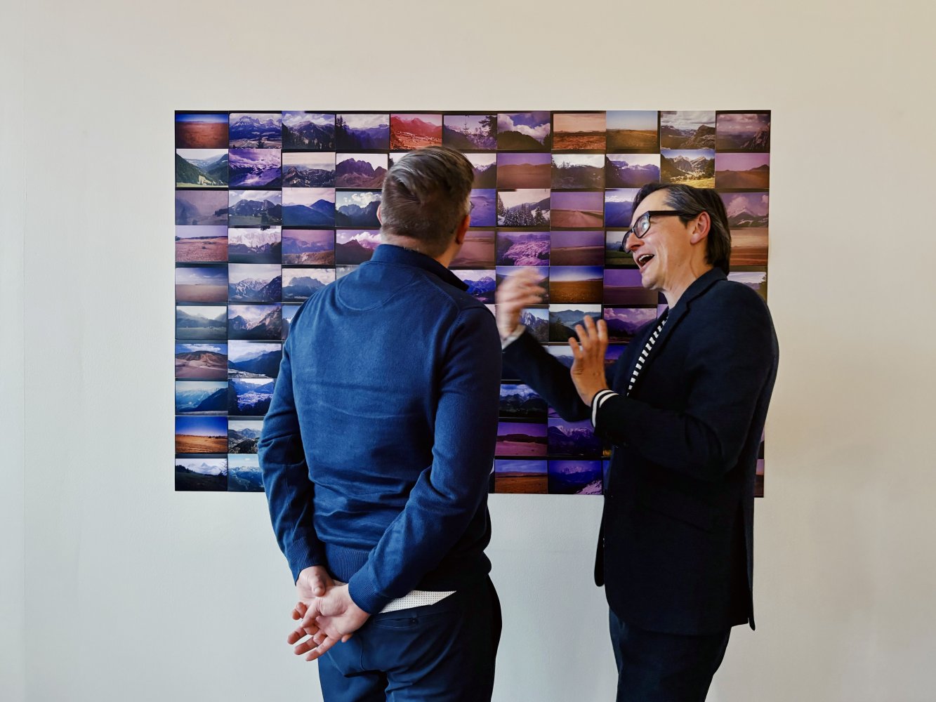 Installationsansicht: Zwei Besucher vor großformatiger Wandarbeit, Raster aus Farbfotografien.