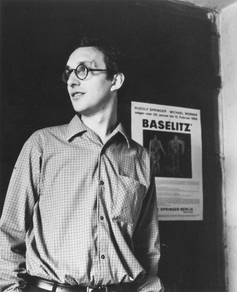 Schwarzweiß-Foto: Mann mit Brille im Profil, vor Ausstellungsplakat mit Schriftzug Baselitz.