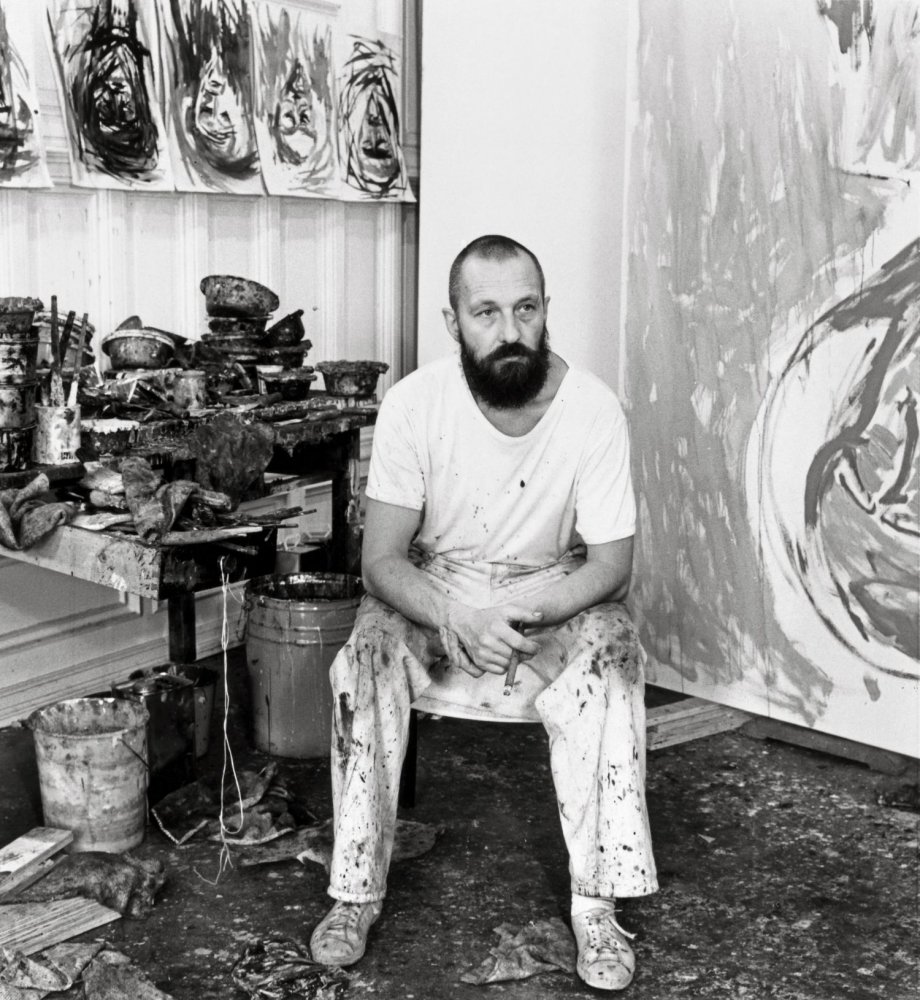 Schwarzweißfoto: Künstlerporträt im Atelier; sitzend; Pinsel, Eimer; gestische Leinwände