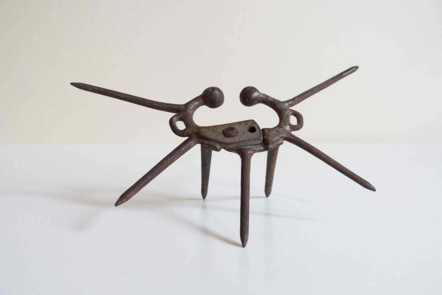 Assemblage aus rostigem Metall; zentrale Platte mit mehreren Stäben und zwei langen Armen.
