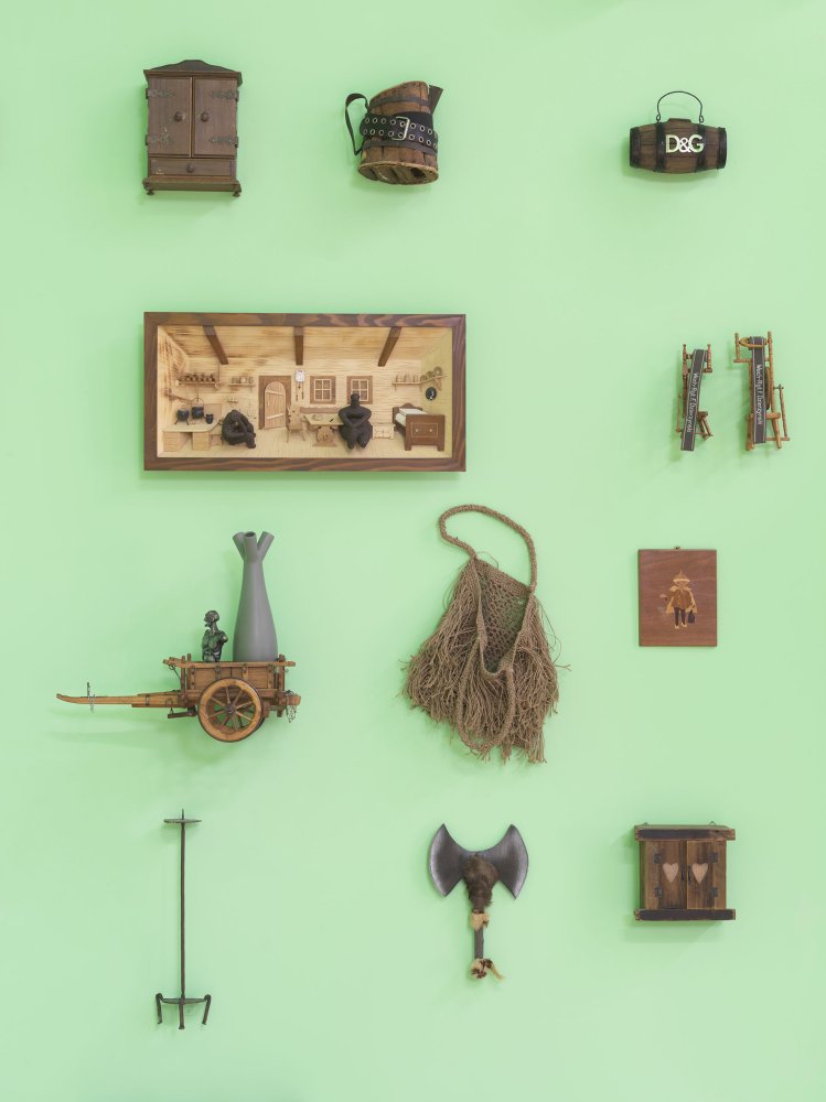 Wandinstallation: kleine Alltagsobjekte in Raster auf mintgrüner Wand, Ausstellungsansicht