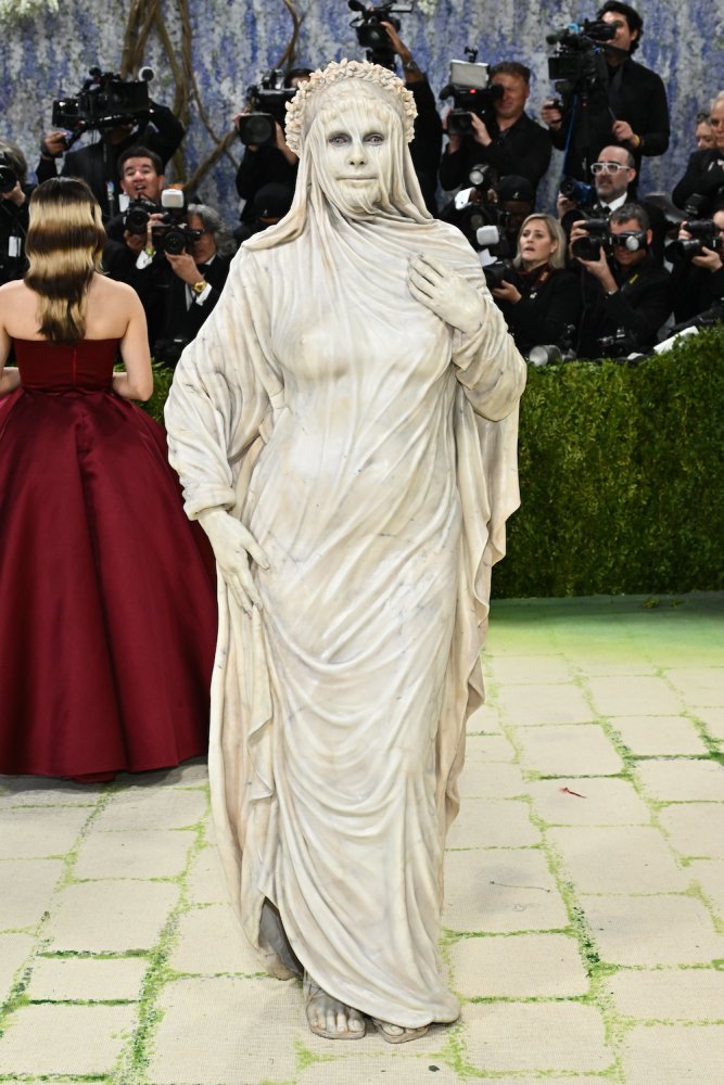 Met-Gala roter Teppich: Person als antike Statue verkleidet, weiße Draperie, Lorbeerkranz.
