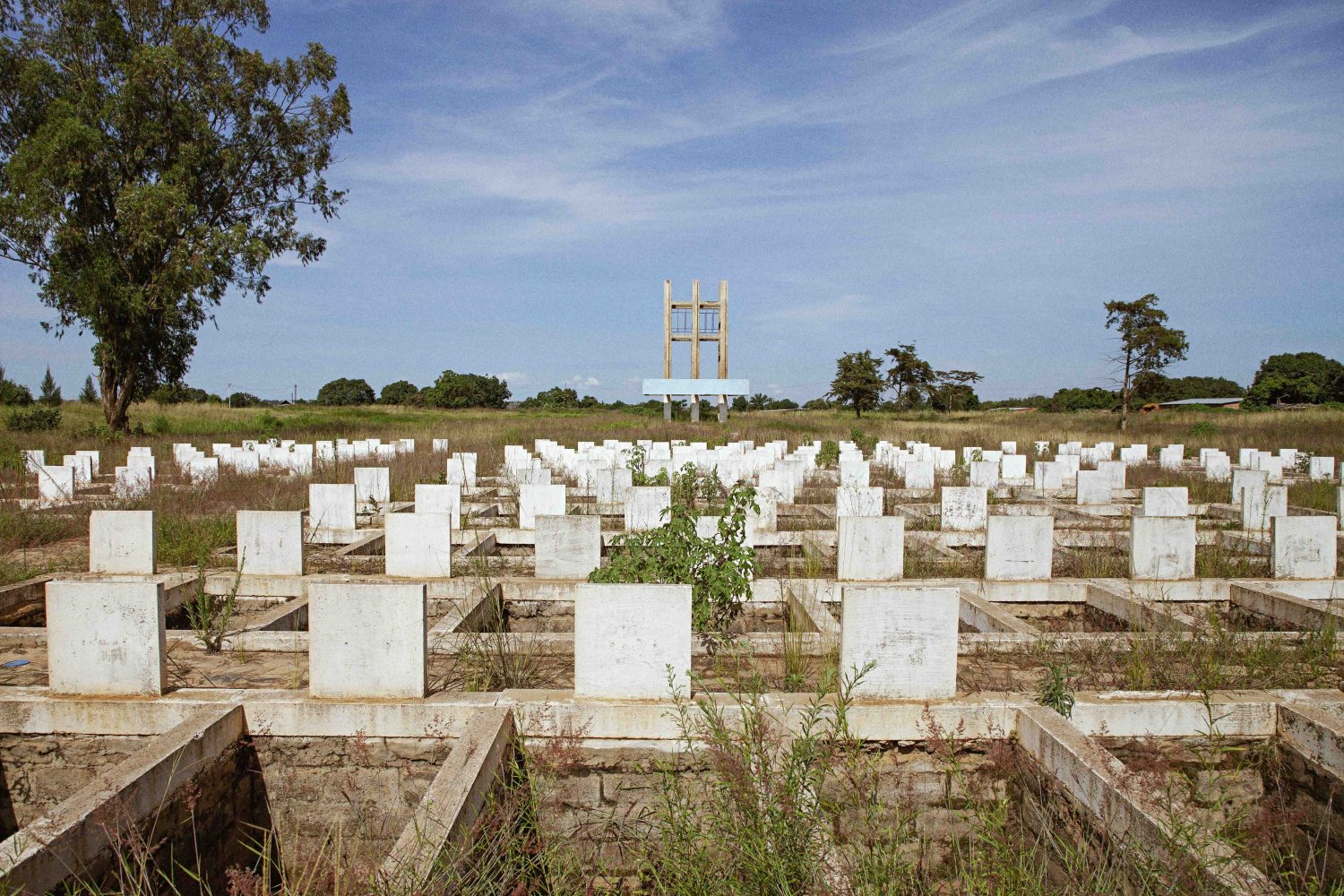 Fotografie: Reihen weißer Grabmale auf weitläufigem Feld; Denkmal und Bäume im Hintergrund.