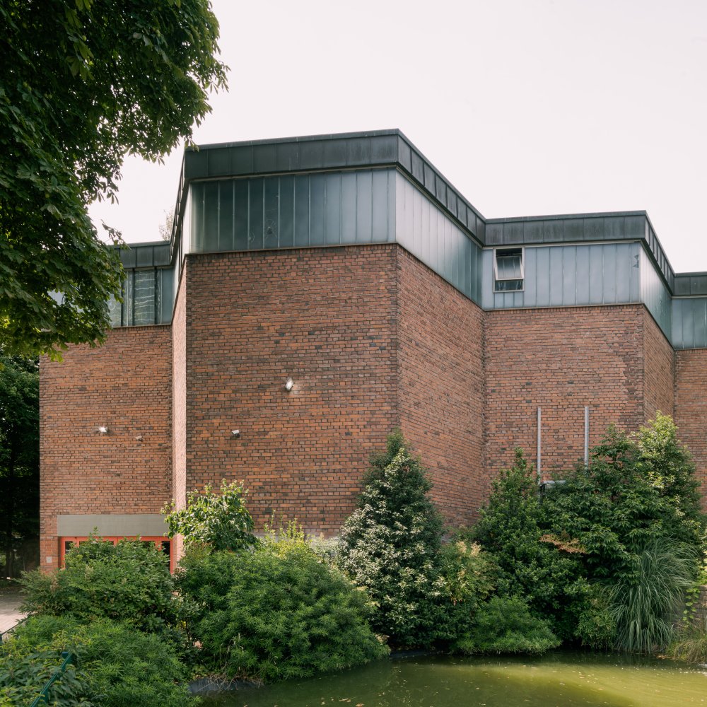 Backsteinbau mit aufgesetztem verglastem Obergeschoss, dichter Garten und Teich.